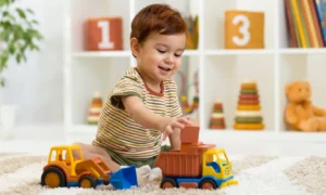 baby sitting with age appropriate toys including playing with his truck toys
