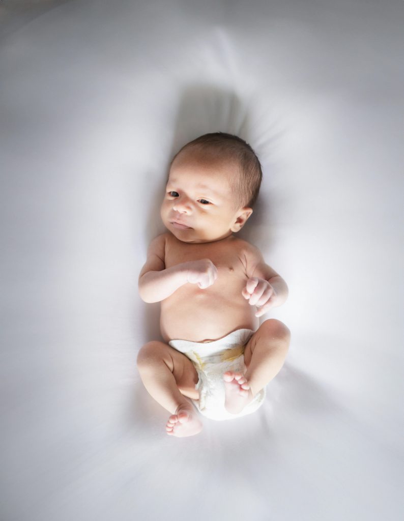 A newborn baby lying on a soft white surface