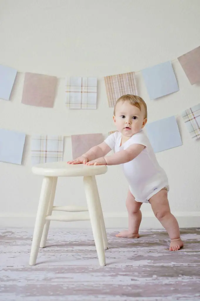 Baby holding white wooden stool